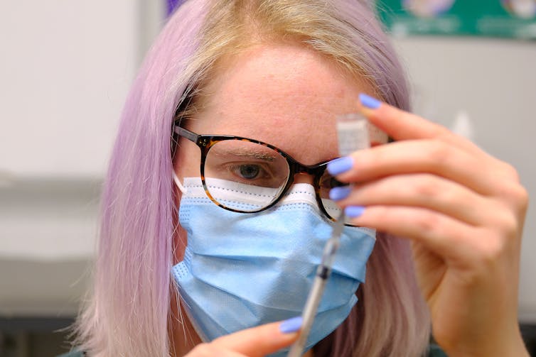 A woman draws up a syringe with the Pfizer vaccine.