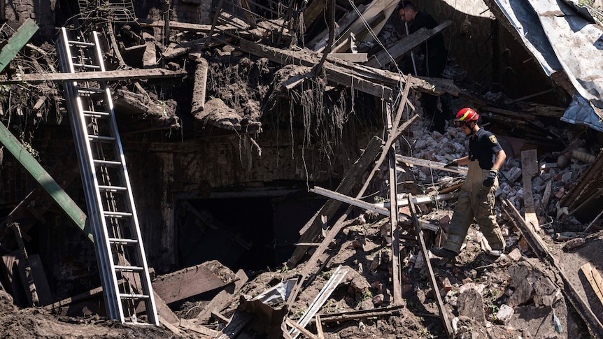 A fireman walks through the rubble of a destroyed building.
